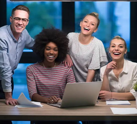 What You Gain Team smiling around a laptop after a successful technology rollout