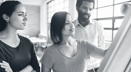 Facilitator leading a leadership and team effectiveness workshop at a whiteboard with colleagues