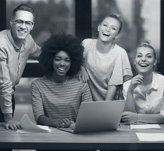 Diverse team smiling around a laptop after successful AI integration consulting project