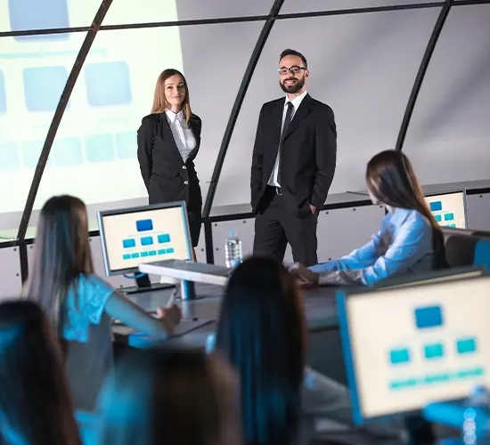 Executive team in a strategy workshop reviewing organizational charts on screens — illustrating who needs strategic research consulting and organizational assessment for high-stakes decisions